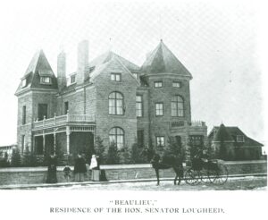 Black and white image c. 1903 of sandstone mansion with people and a carriage in front.