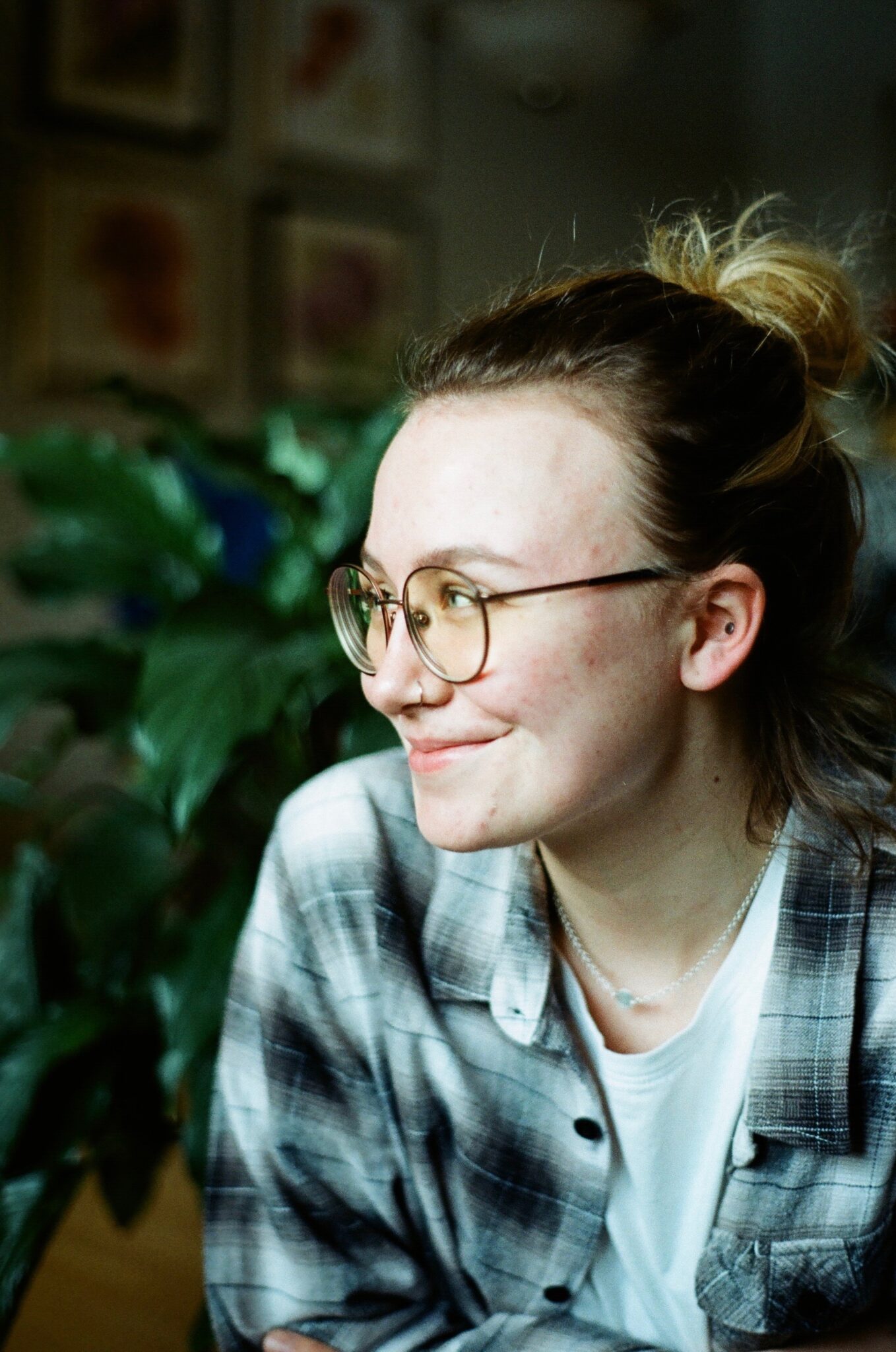 Side profile of person with their light hair pulled back in a bun, glasses, and a grey plaid shirt.