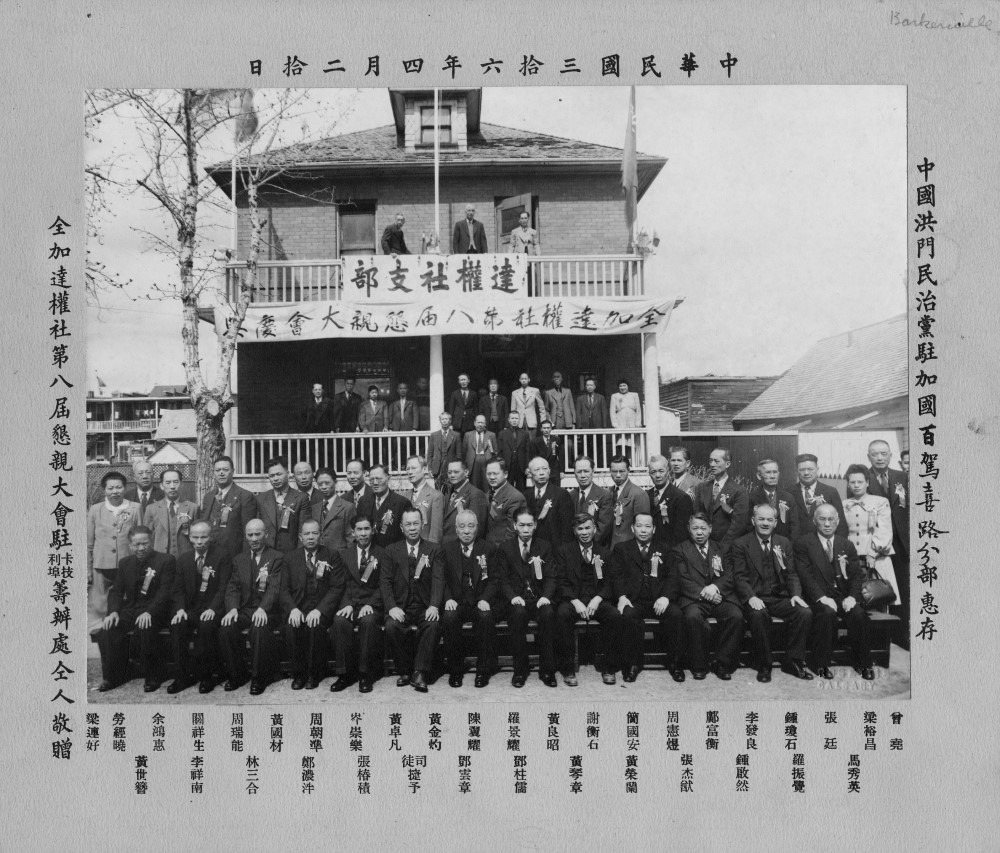 Big group photo in front of building. Black and white. Chinese characters listing names at the bottom, along the sides, and above image.f 