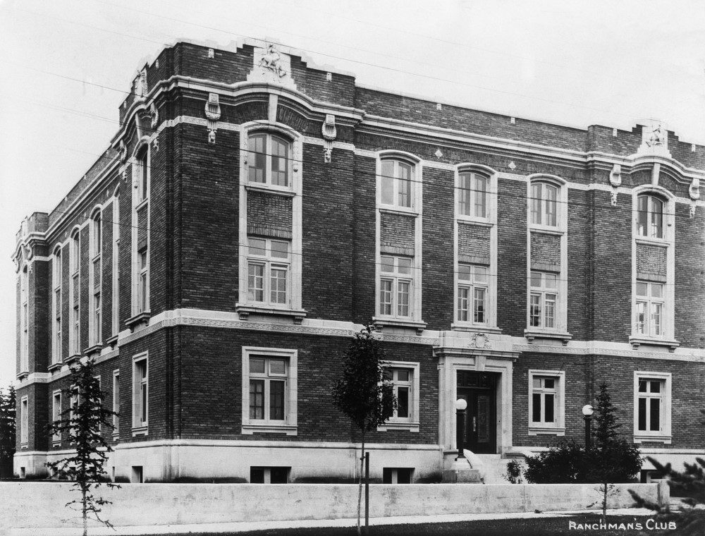 Black and white photograph of a three story brick building taken from a corner angle.